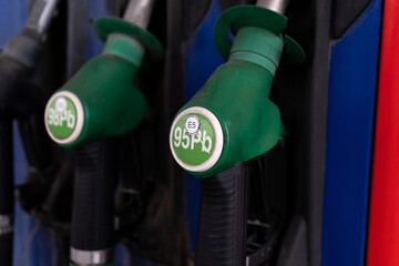 Fuel nozzles with hoses, attached to the gas station column, gasoline pump stand or dispenser machine at self-service petrol filling station.