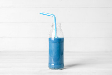 Glass bottle of blue smoothie on white background