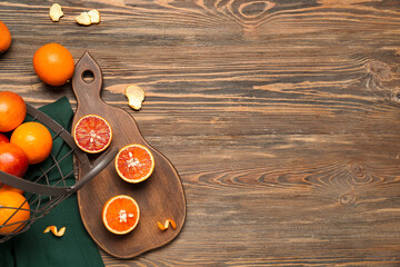 Board and metal basket with tasty blood oranges on wooden background