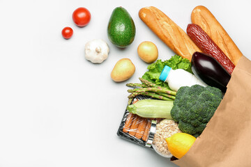 Paper bag with vegetables, cereal, bread and milk on grey background