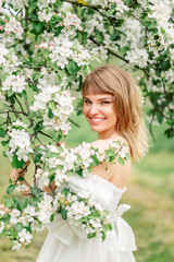 Obraz na płótnie Canvas Happy beautiful smiling young woman in flowering spring garden