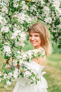 Happy beautiful smiling young woman in flowering spring garden