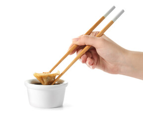 Woman dipping tasty Chinese jiaozi into sauce on white background