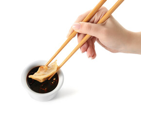 Woman dipping tasty Chinese jiaozi into sauce on white background