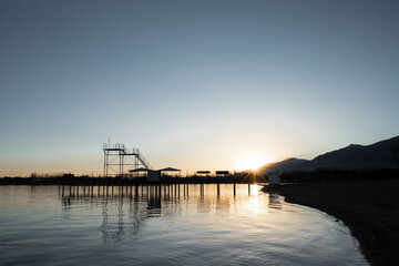 Fototapeta na wymiar Scenic Mountain Lake Pier at Sunset with Sun Rays