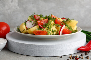Plate of tasty Potato Salad with vegetables on grey background