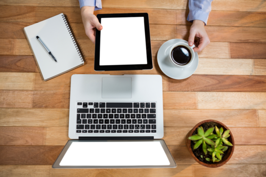 Cropped image of businesswoman using digital tablet while holding coffee cup