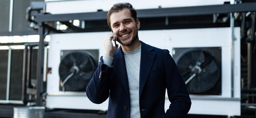 portrait of a european male journalist talking on the phone against the backdrop of a dark business center building