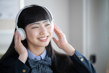 笑顔でヘッドフォンで音楽を楽しむ女子高生　正面