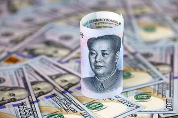Chinese yuan banknote rolled up on US dollars background. Concept of trade war between the China and USA, economic, sanctions and investment