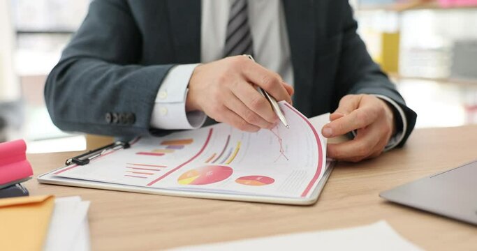 Businessman leafing through documents with graphs at desktop in office closeup 4k movie slow motion. Business strategy and presentation concept 
