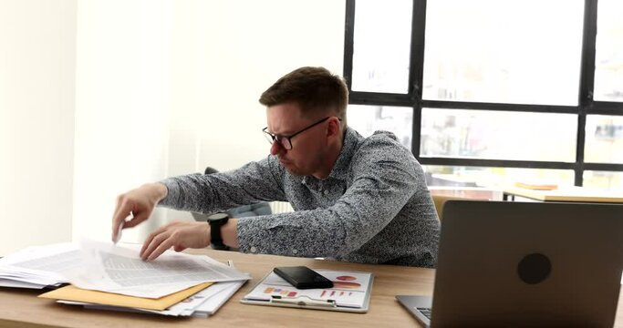 Businessman in glasses looking for document at table in office 4k movie. Difficulties and problems in paperwork concept