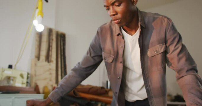 Focused african american craftsman brushing leather in leather workshop