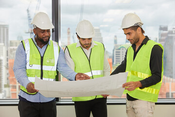 group of engineers holding white paper or blueprint and talking about projects on construction site