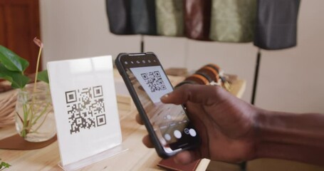 Hand of african american craftsman scanning qr code in leather workshop - Powered by Adobe