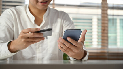 Man hand holding credit card and mobile phone making orders via internet or transaction on mobile banking application