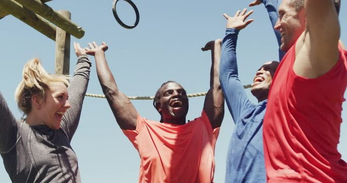 Happy fit diverse group making hand stack and cheering after completing obstacle course