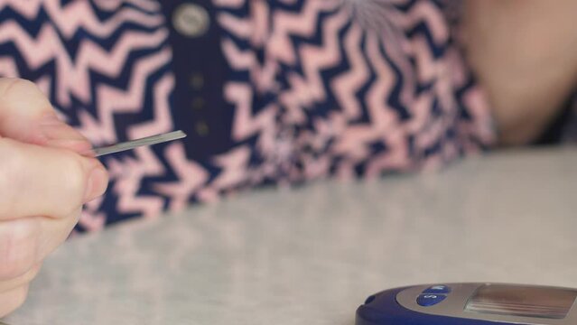 close-up of an elderly woman's hand measuring blood sugar with a glucometer. selective focus health care in old age. be healthy concept.strips for glucometer