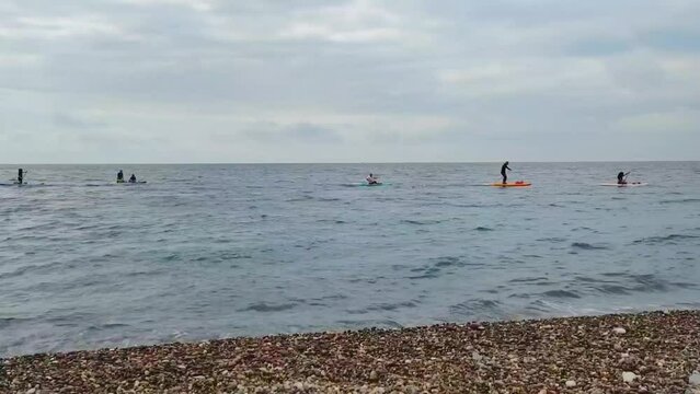 People are floating on a wakeboard in an open blue sea against a cloudy sky