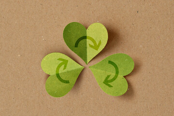 Recycling symbol with heart shaped leaves on recycled paper background - Concept of ecology and recycling