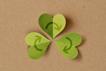 Recycling symbol with heart shaped leaves on recycled paper background - Concept of ecology and...