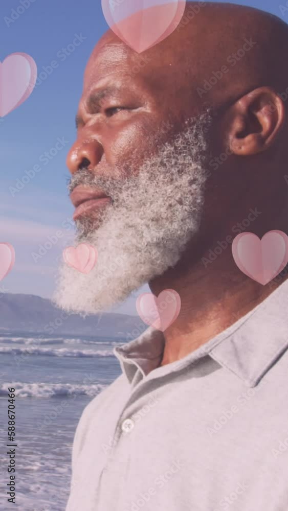 Wall mural Animation of hearts over senior african american man at beach