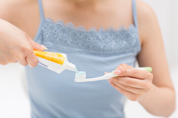 歯ブラシに歯磨き粉を付ける女性の手元