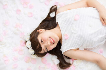 Naklejka premium 床にまかれた花びらの上に寝転ぶ女性