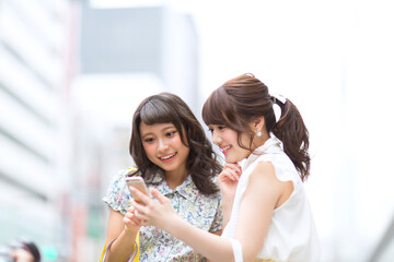 街中でスマートフォンを見る女性2人