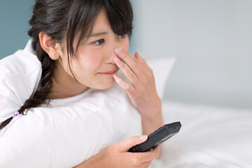 ベッドの上でリモコンを持ち感動する女性