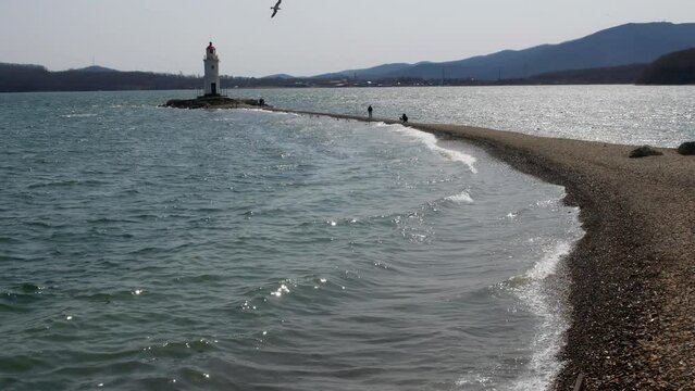 Marine lighthouse on the peninsula. A lighthouse on a coastal spit jutting into the sea.