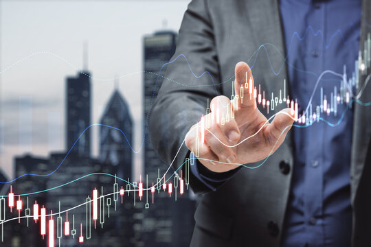 Close up of male hand pointing at glowing upward forex chart on blurry night city background. Trade, finance and stock concept. Double exposure.