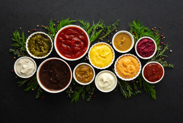 Different types of sauces in bowls with seasonings, rosemary and dill, thyme and and peppercorns, top view, copy space