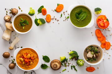 Mushroom and lentil cream soup, bean, carrot and tomato soup, broccoli and spinach soup on white background with cooking ingredients, copy space
