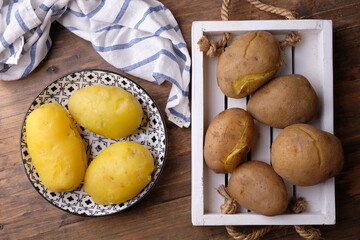 boiled potatoes on a wooden cutting board and peeled boiled potatoes on a ceramic plate with an Asian pattern. carbohydrate. kentang rebus. 