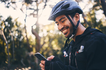 Cycling, phone and smile with man in nature for search, networking and connection. Relax, happy and social media with male cyclists in forest park for training, sports and internet browsing