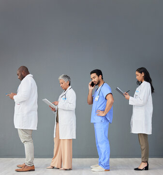 Doctors Standing In A Row Isolated On Wall Background With Tablet, Phone Call And Medical Paperwork For Hospital. Healthcare People Or Nurse Technology In Waiting Room For Clinic Or Hiring Research