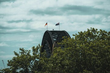 View of the Sydney Harbour bridge top with the flags under a cloudy sky