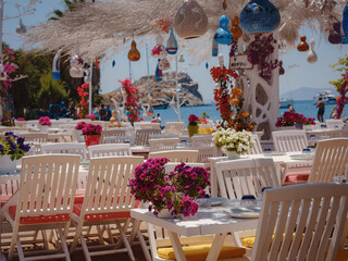 Bodrum summer travel to Turkey. Aegean fish restaurant table in Gumusluk Town, Bodrum, Turkey. Restaurant tables and chairs are in the sea