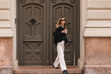 Happy beautiful stylish woman having good fashion white jeans pants, black shirt walking by street,...