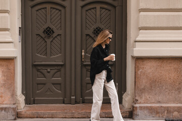 Happy beautiful stylish woman having good fashion white jeans pants, black shirt walking by street,...