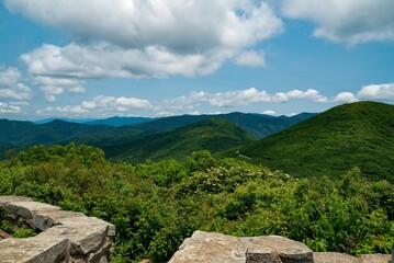 Landscape view of the green hills with lush trees against a blue clouded sky