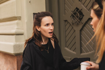 Quarrel two friends. Two women screaming at each other. Two young women argue near door outdoor on...