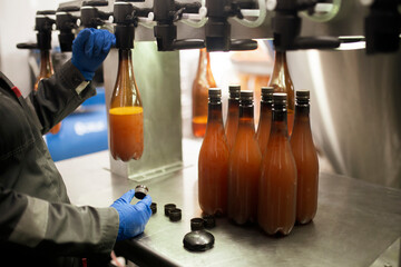 employee on the factory filling new plastic bottle with beer from faucet