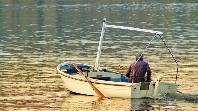 Male fisherman in a small boat peacefully floating down a river