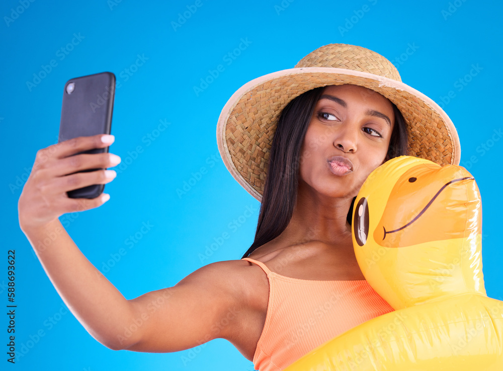 Poster Happy woman, selfie and swimming vacation for social media or profile picture with inflatable duck against a blue studio background. Excited female model in summer swimwear for photo, travel or trip