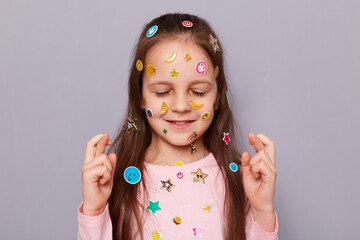 Portrait of smiling adorable little brown haired little girl covered with stickers posing isolated...