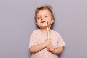 Image of satisfied girl kid holding tooth brush, taking care of her teeth health from early...