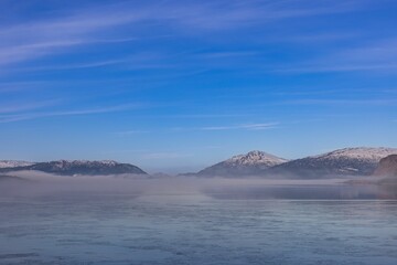 mountains with some clouds and mist in the water below them