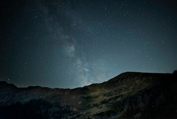 Obraz na płótnie Canvas Low-angle of a night starry sky with a mountain silhouette background